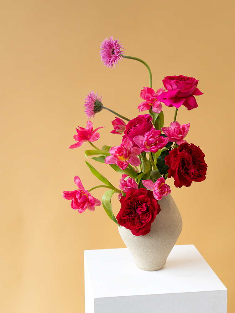 Vancouver Florist - Vancouver Flower Delivery - Valentine's Flowers, Vase with pink and red flowers on a white pedestal against a beige background